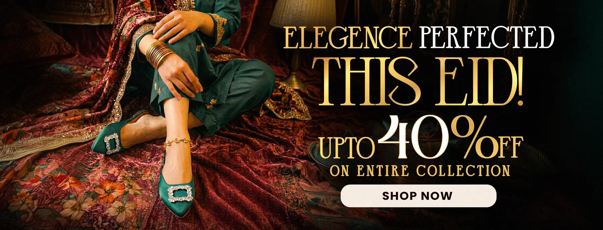 Promotional banner for an Eid sale featuring a model in dark teal traditional clothing and matching teal shoes with square embellished heels, seated on a richly patterned red and gold rug. The right side contains large gold and white text reading 'ELEGANCE PERFECTED THIS EID! UPTO 40% OFF ON ENTIRE COLLECTION' with a white 'SHOP NOW' button below.